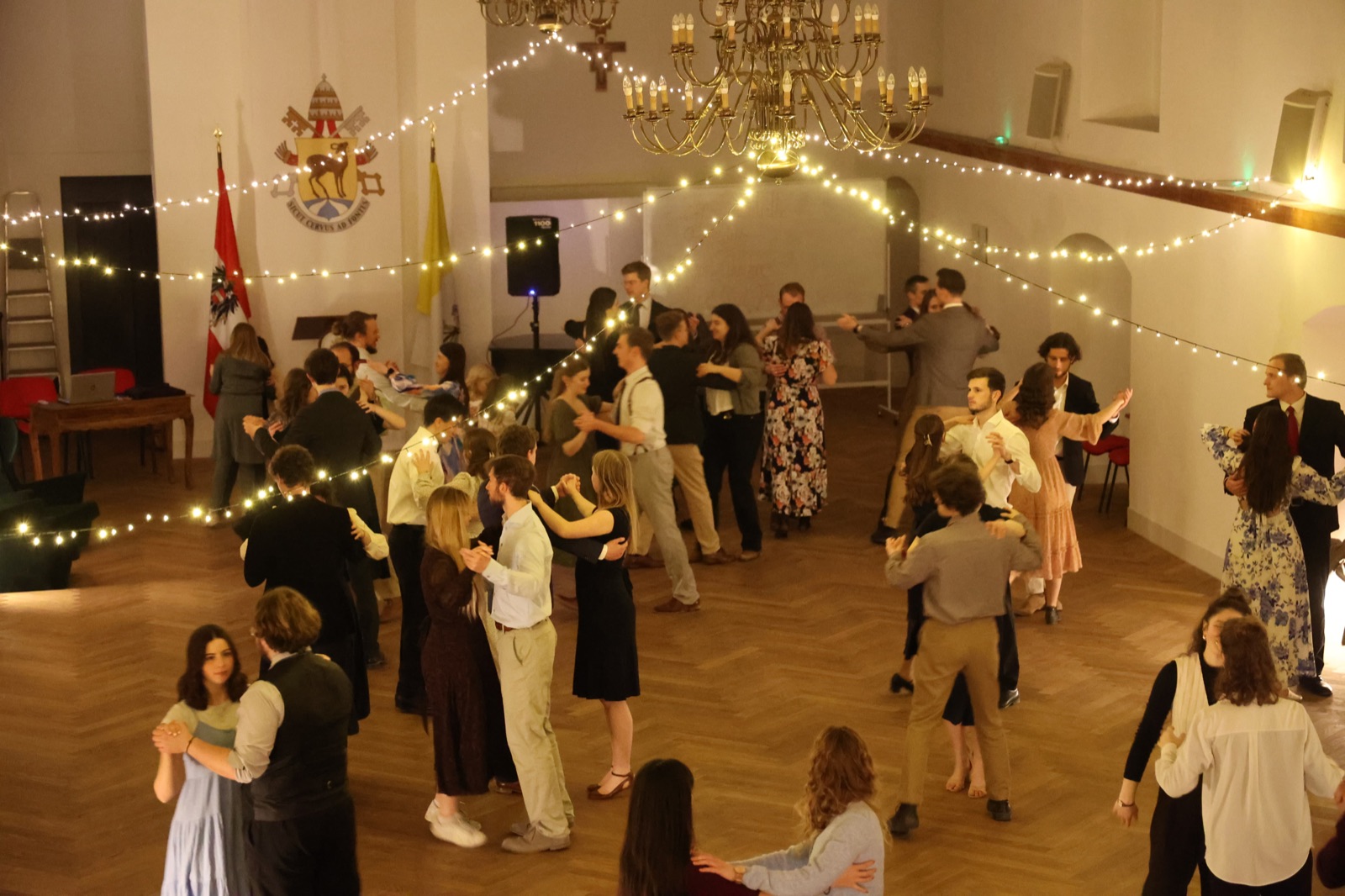Couples dancing at the university ball under chandeliers