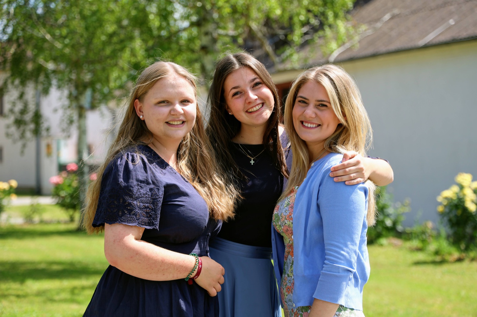 Three students arm in arm, laughing