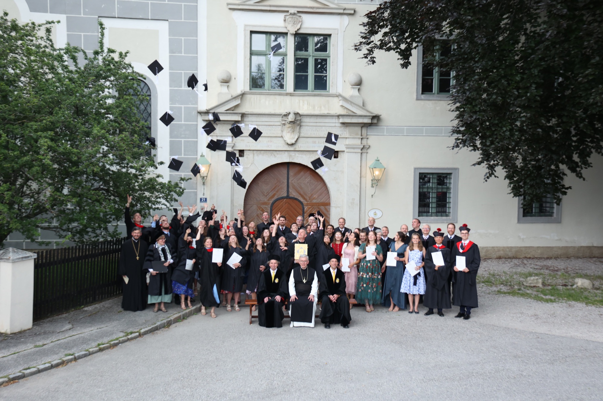 Graduates throwing their caps in the air in front of a baroque facade