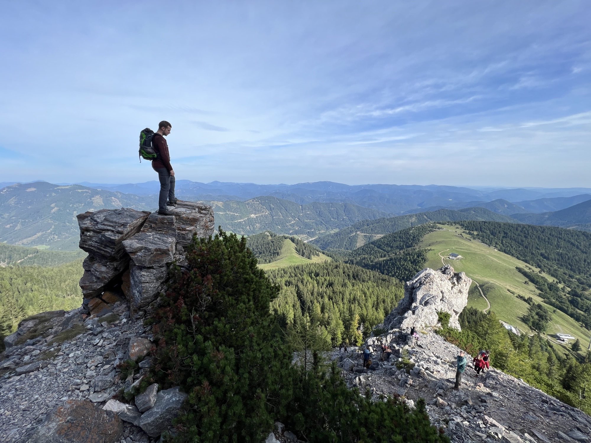 A hiker standing on a rock ledge above a wide alpine valley