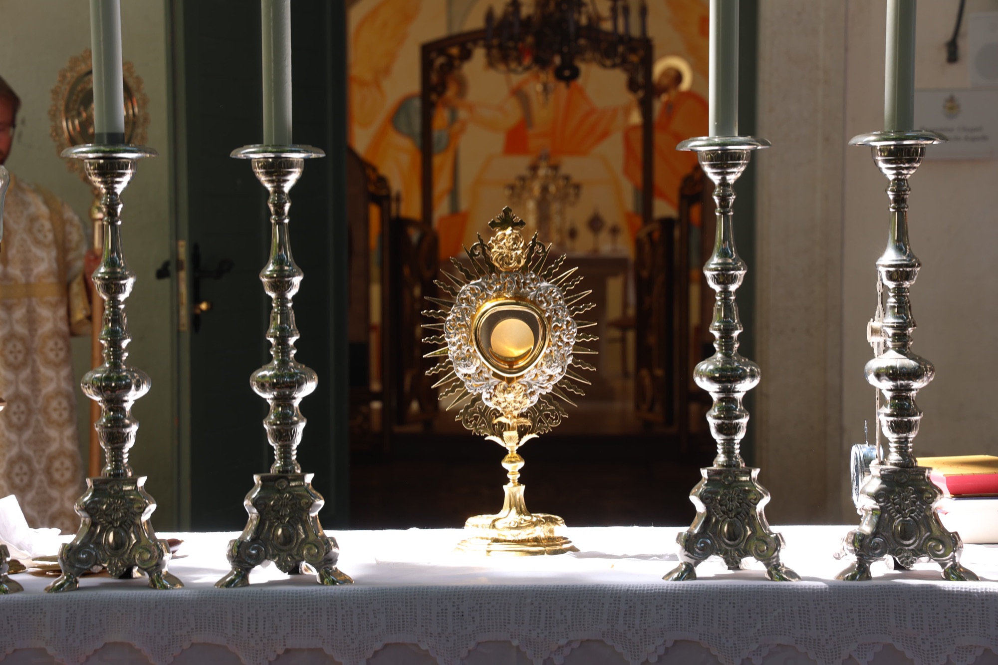 Monstrance with the Blessed Sacrament on the altar between silver candlesticks
