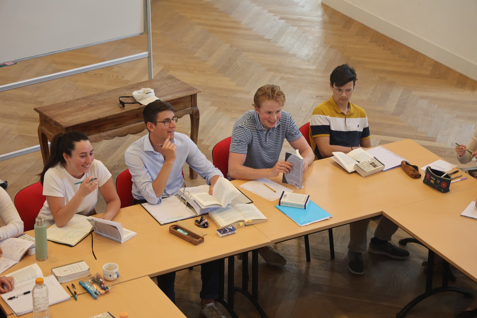 Students around the seminar table with books, laughing